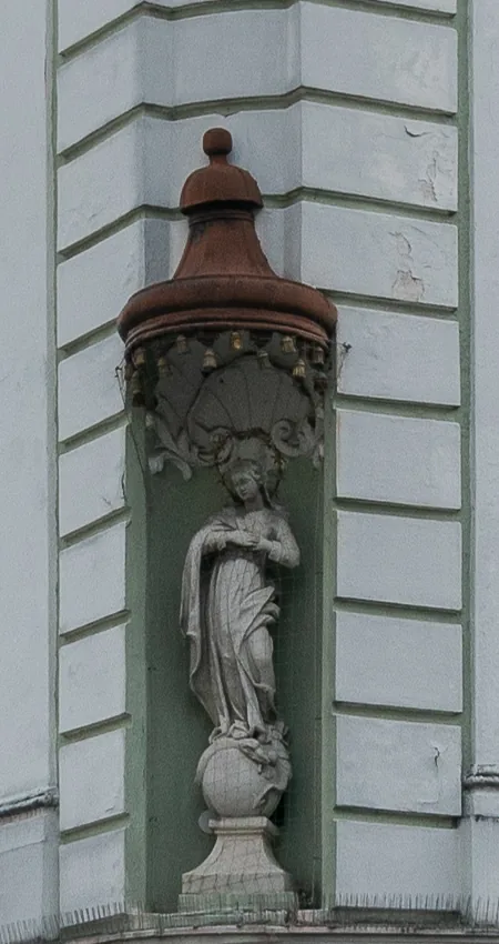Barocke Madonnenfigur unter einem kupfernen Baldachin in der Ecknische der Fassade